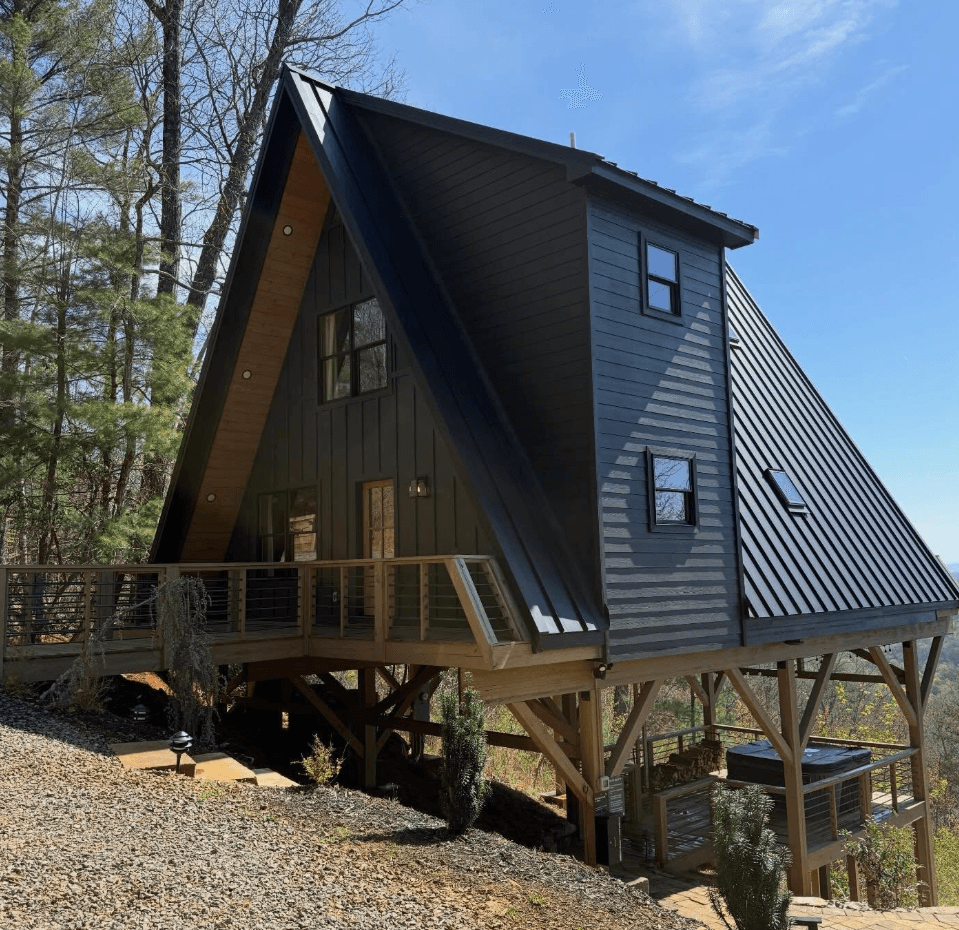 Modern A-frame cabin with dark siding in a wooded North Georgia setting