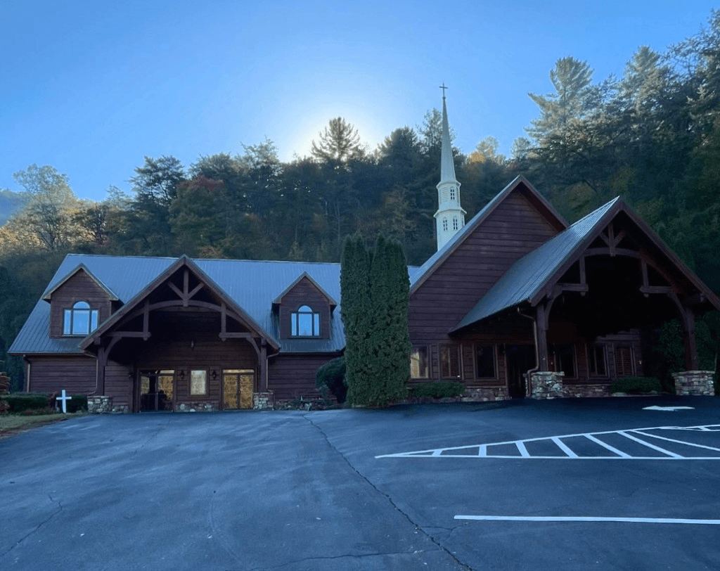 Large commercial church building with clean parking lot in a wooded mountain setting