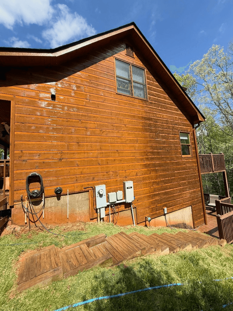 Log cabin exterior with wet wood siding after soft wash cleaning