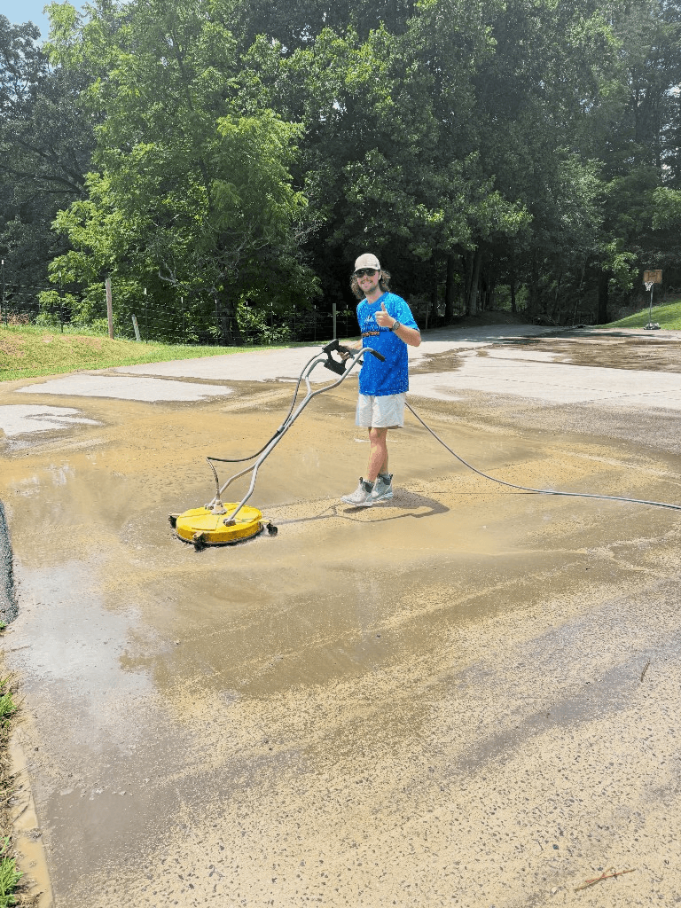 Technician using a professional surface cleaner on a large concrete driveway